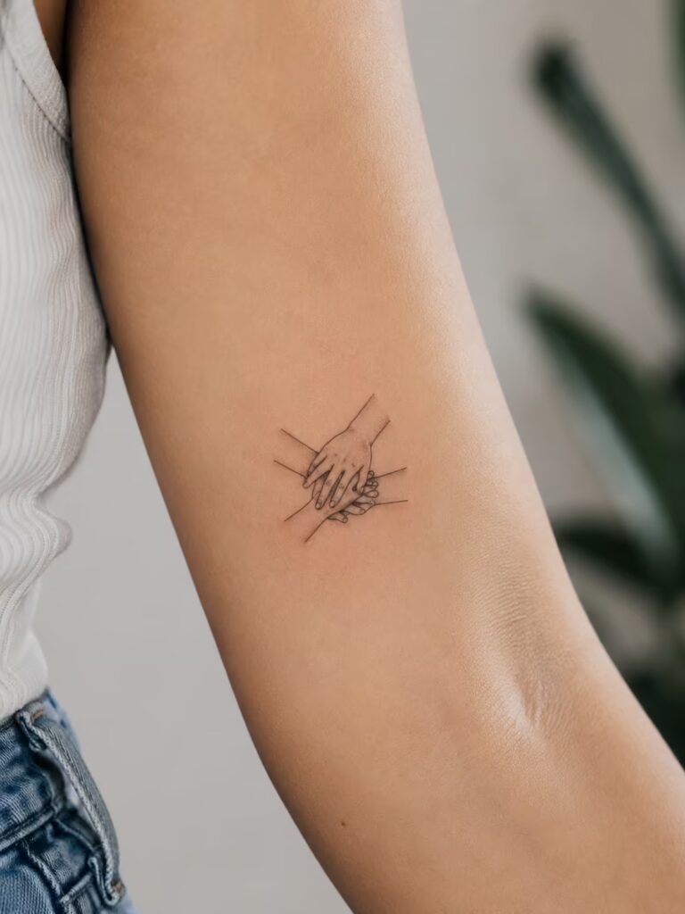 A Small Bestie Tattoo of Three Hands in a Team Huddle on the Inner Upper Arm
