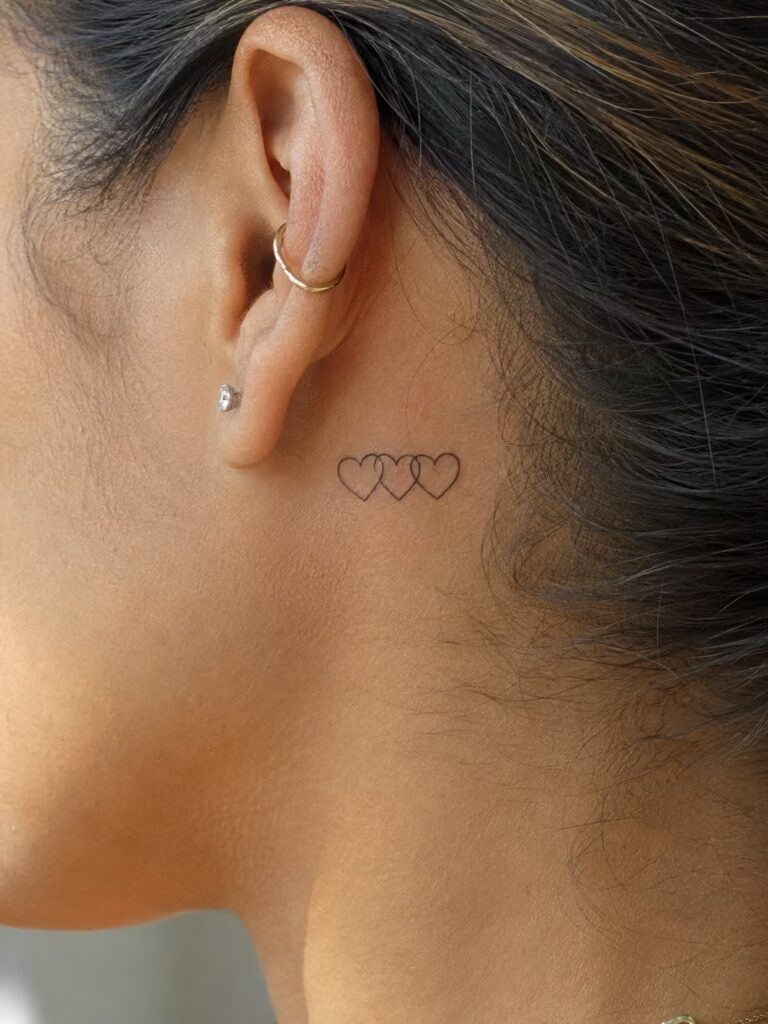 A Small Bestie Tattoo of Three Linked Hearts on the Neck Behind the Ear
