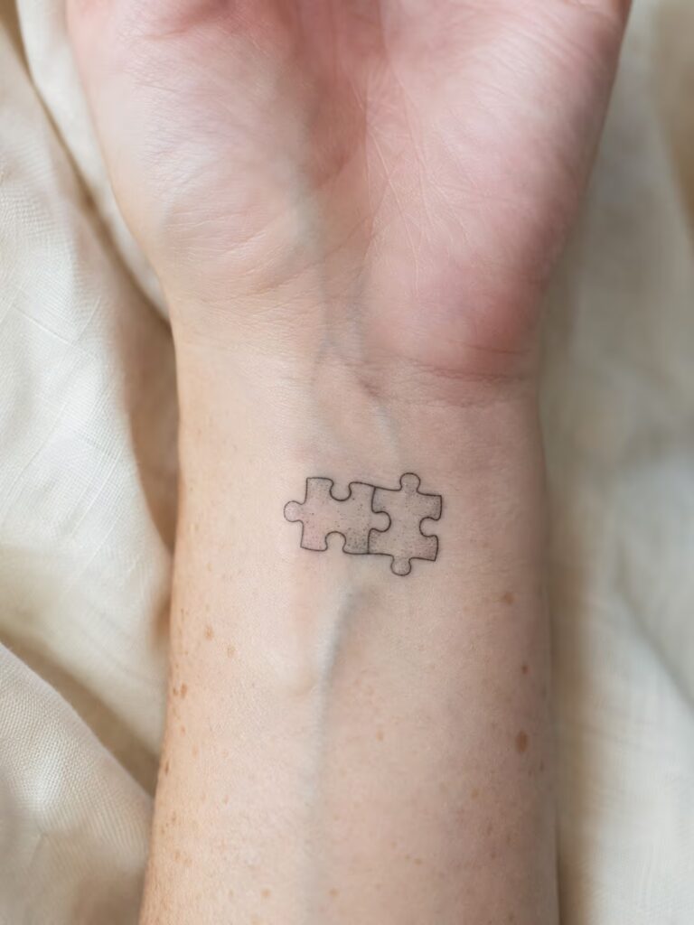 A Small Bestie Tattoo of Two Puzzle Pieces Locked Together on the Inner Wrist